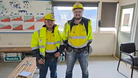 Adjie and a colleague in Merz hi-vis jackets, hard hats with cap lamps and safety glasses at a site office